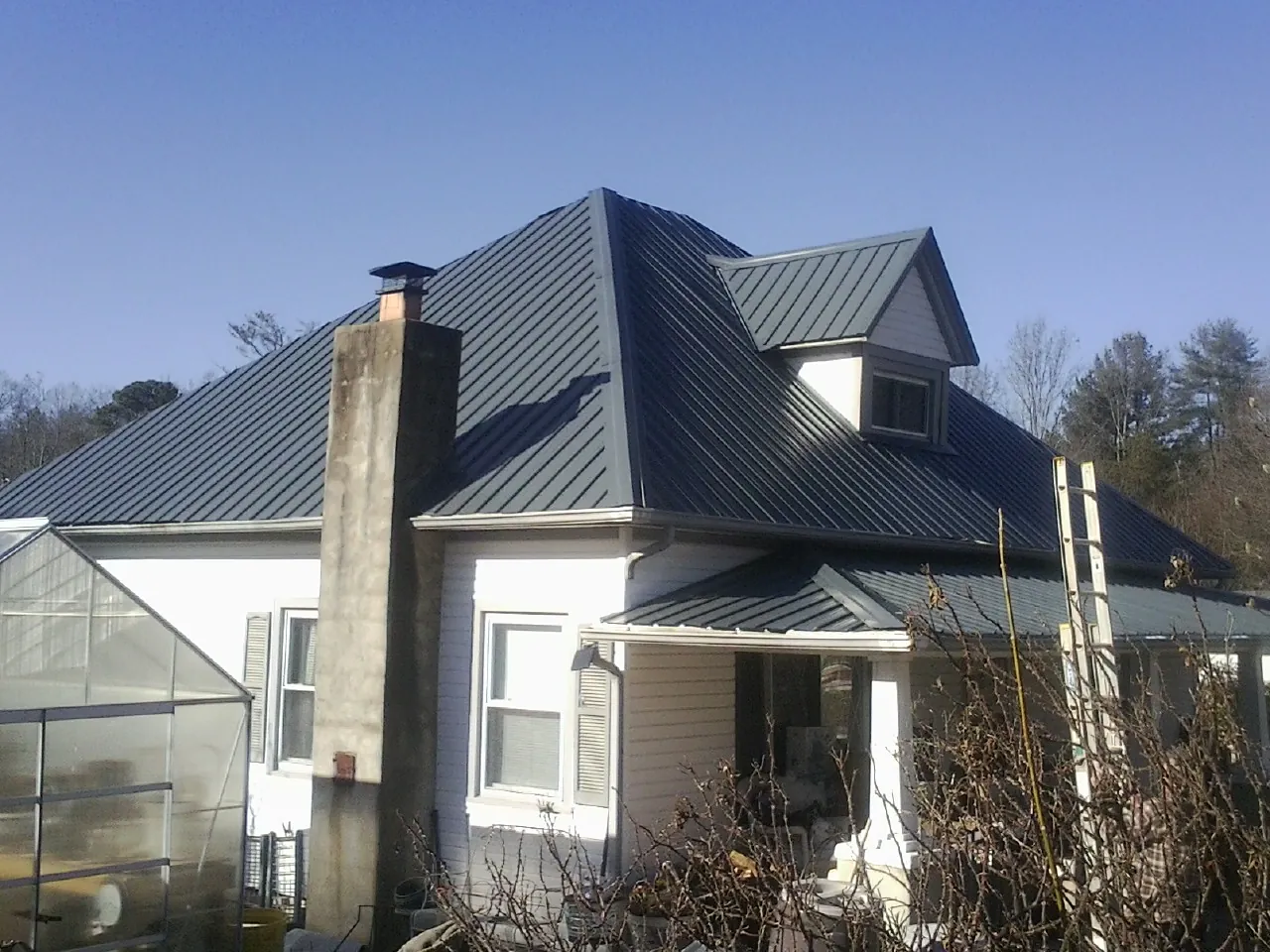 Dark blue standing seam metal roof on a white farmhouse with dormer — Slate & Tile Roof Repair by Roofing Brothers in Alloway