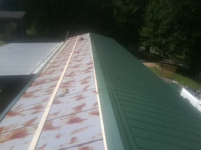 Old rusted panels beside newly installed green metal roofing — Wind Damage Roof Repair by Roofing Brothers in Alloway