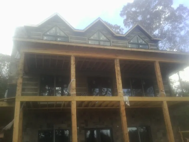 Dormers and porch framing on a large log home under construction — Roof Coating work by our crew in Alloway