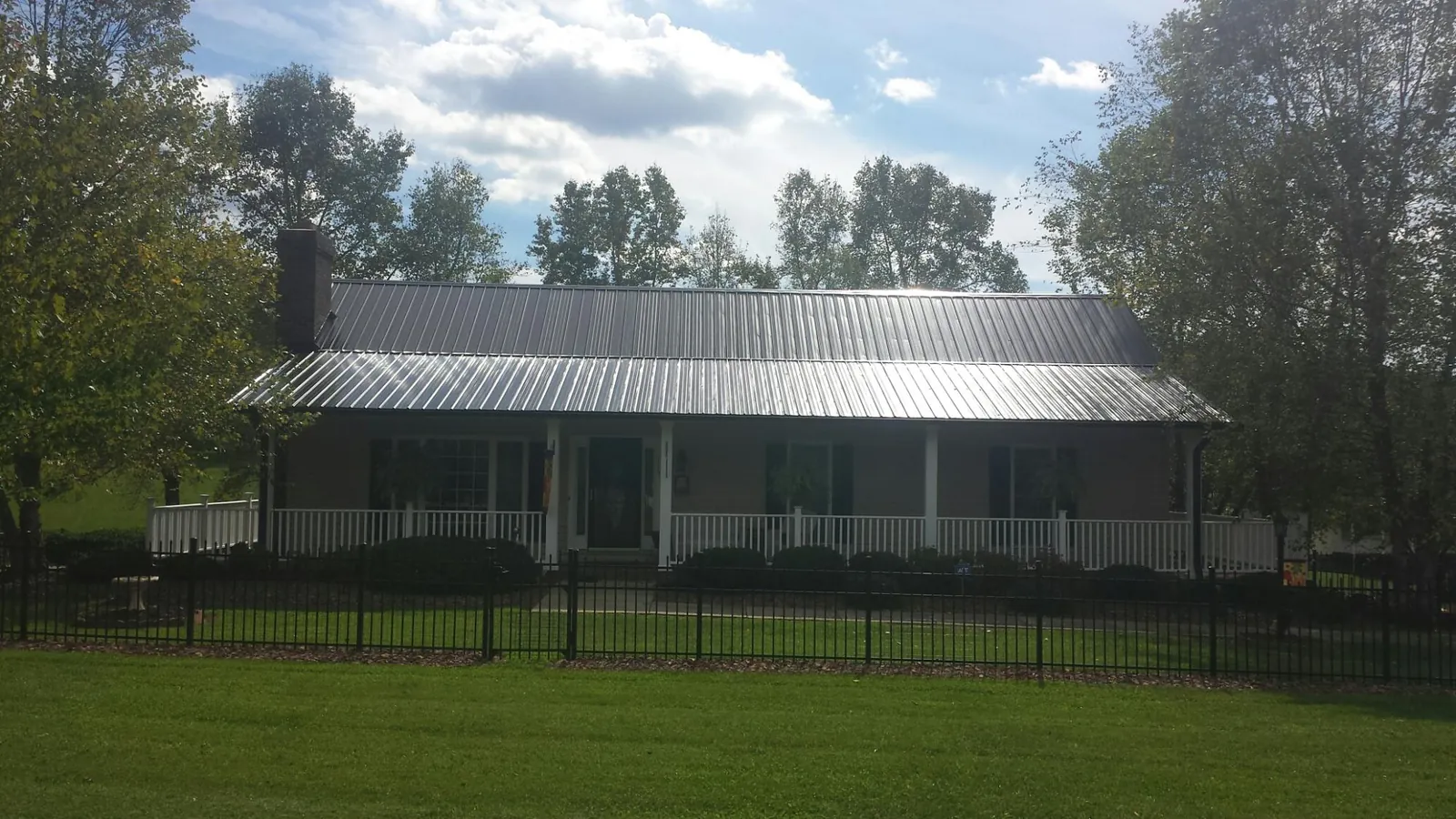 Gray metal roof on a brick ranch with a full width front porch — Gutter Guard Installation work by our crew in Alloway