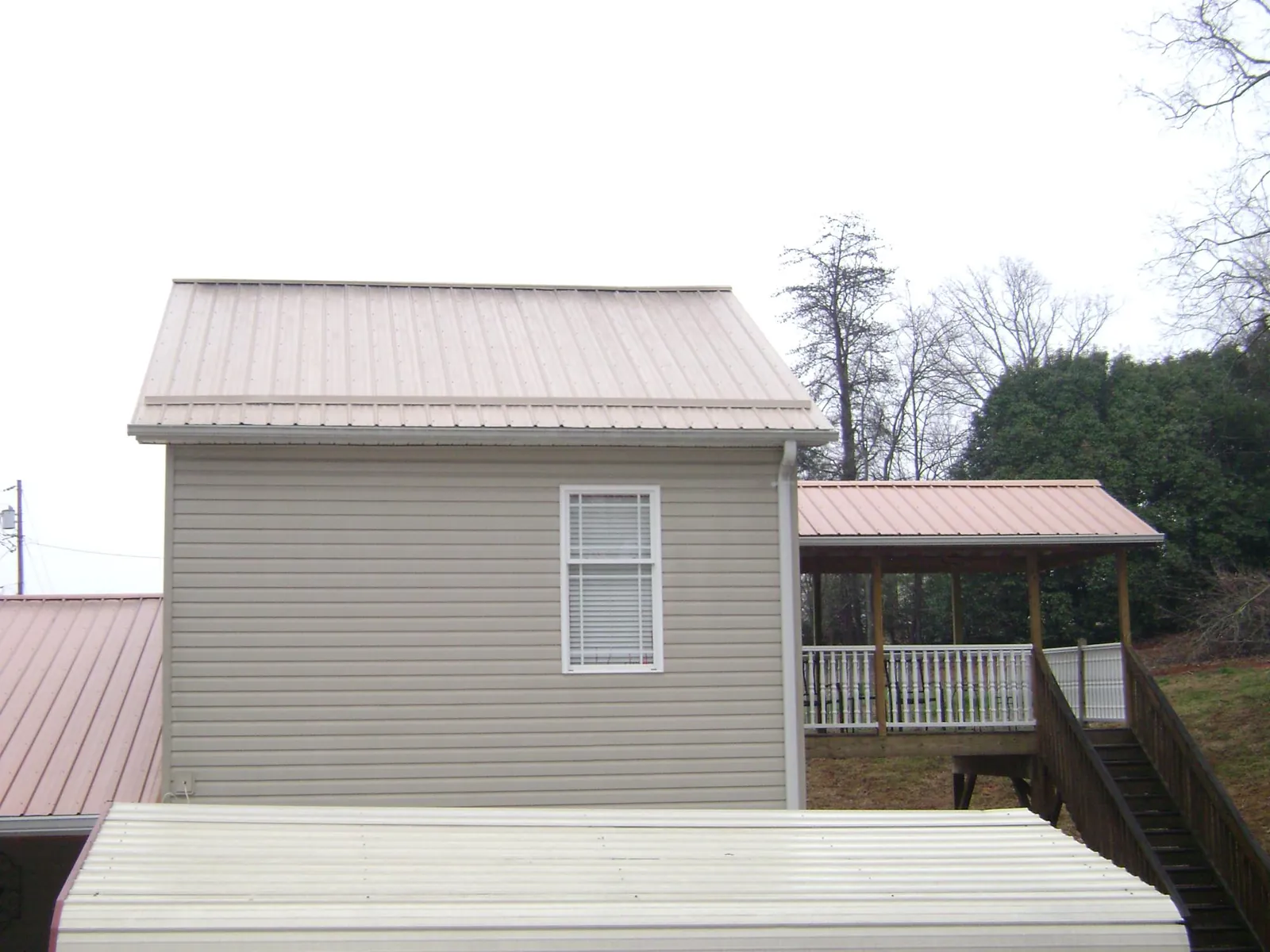 Tan metal roofs on a two story addition and attached porch, from a Roof Replacement job in Alloway
